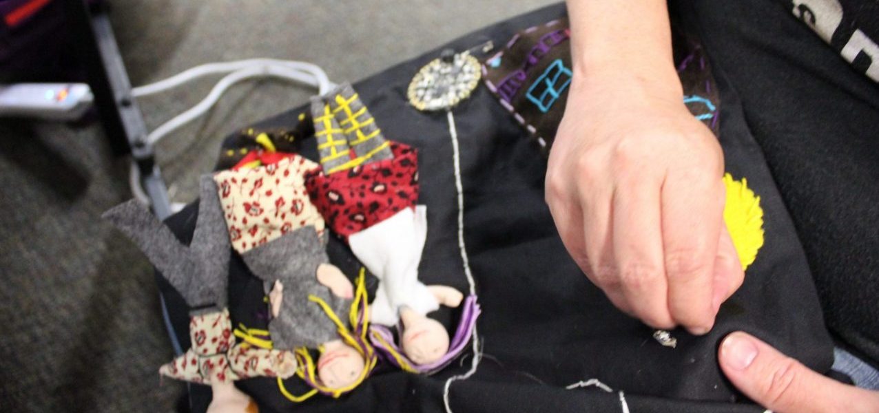 Close up of a parent sewing an LED to e-textile project